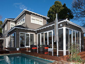 Grey Exterior Weatherboard House with Backyard Pool and White Trims and Wooden Deck